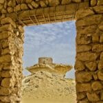 Skała na pustyni Al-Ula widziana przez ruiny z piaskowca