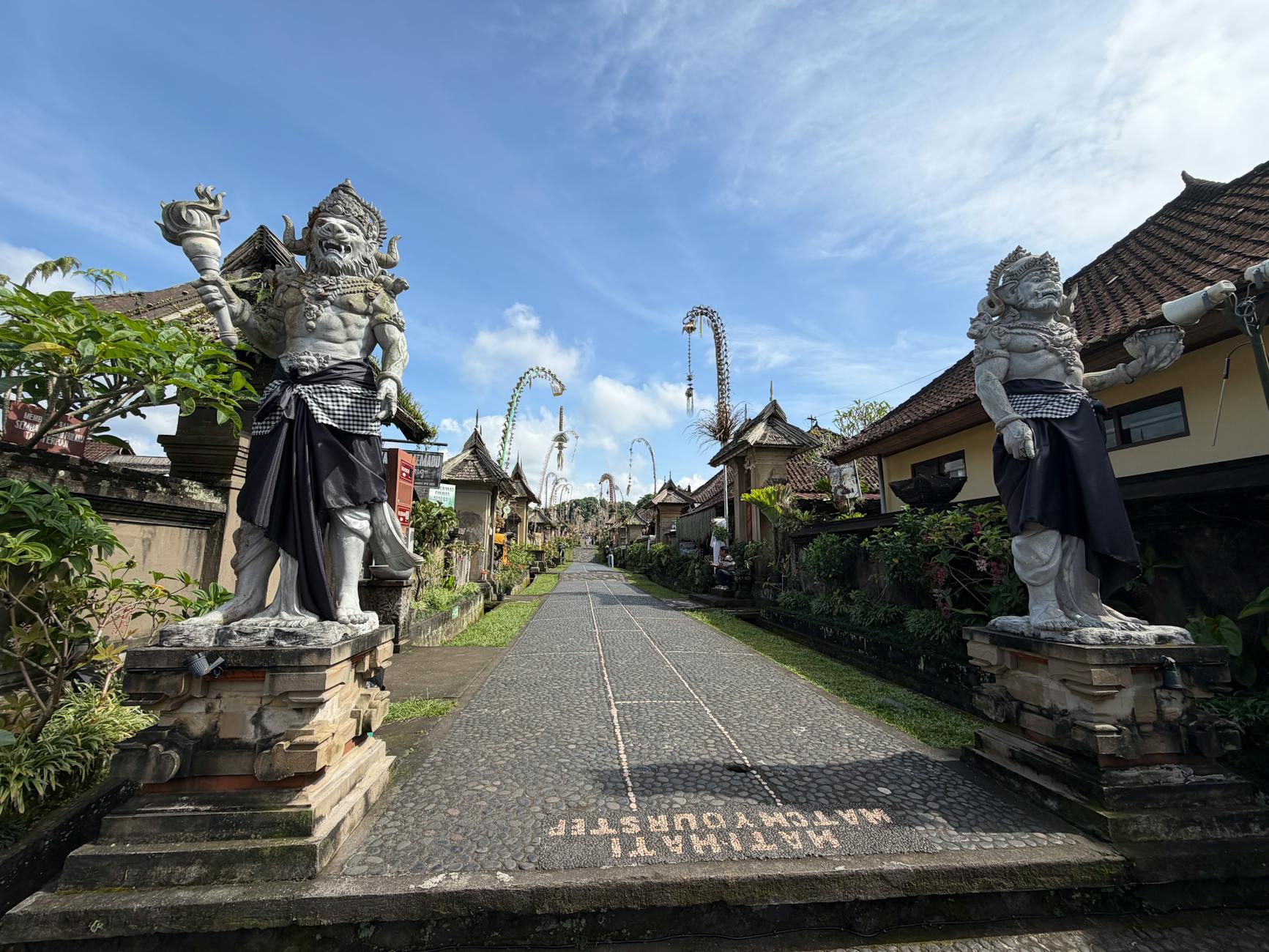 Spokojna ulica balijskiej wioski z kamiennymi posągami strażników