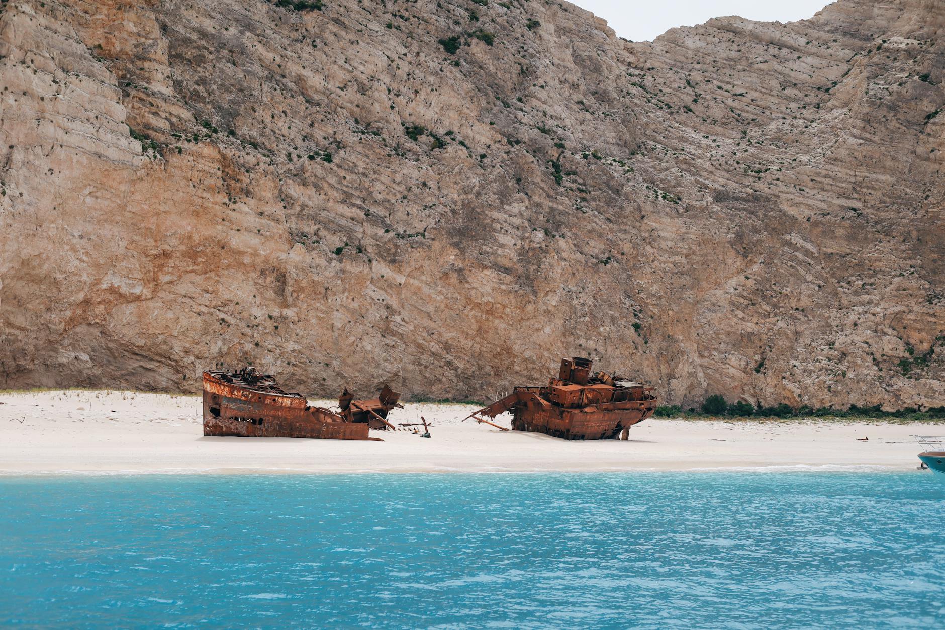 Wrak statku na ustronnej plaży w Grecji otoczonej wysokimi klifami