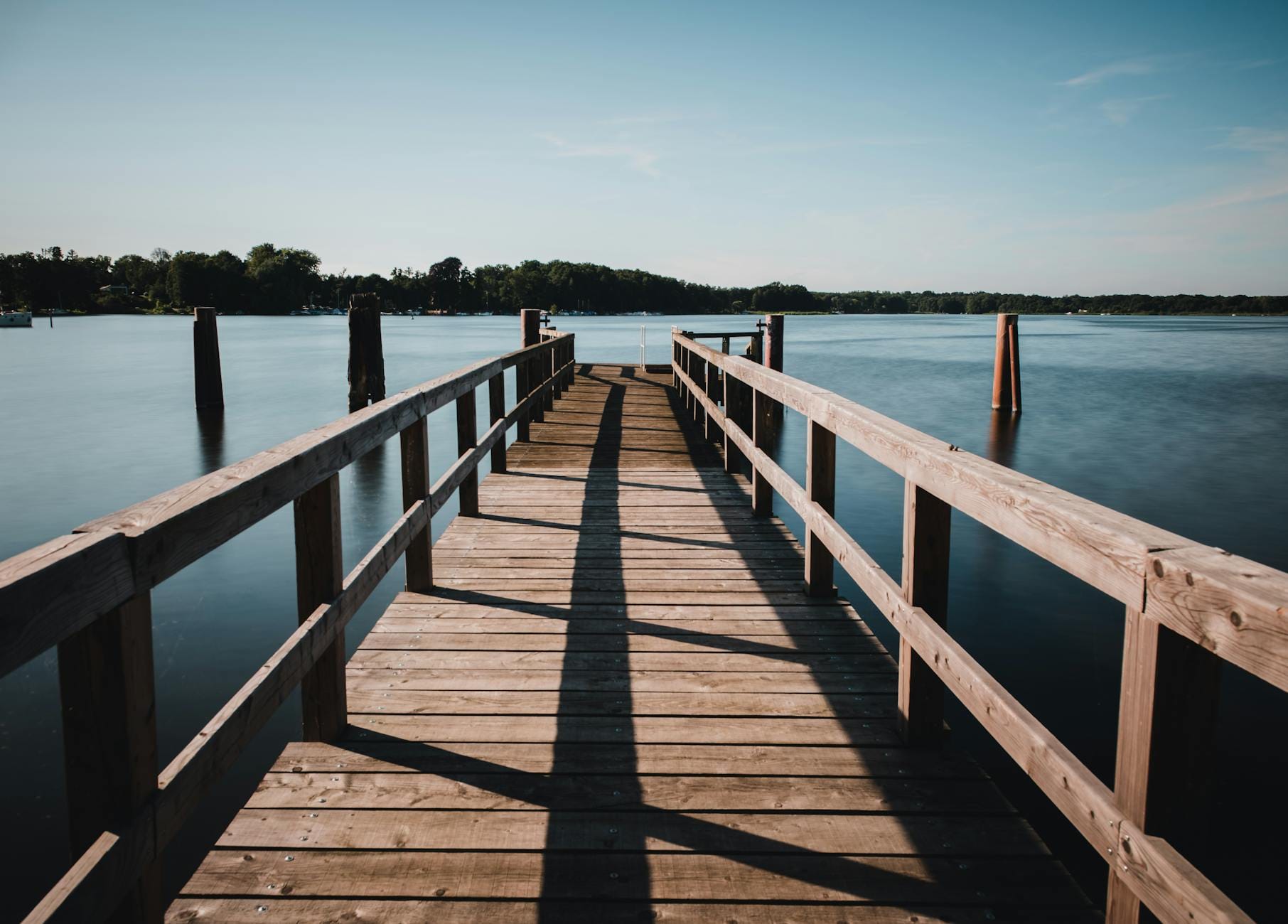Drewniany pomost nad spokojnym jeziorem w letni dzień