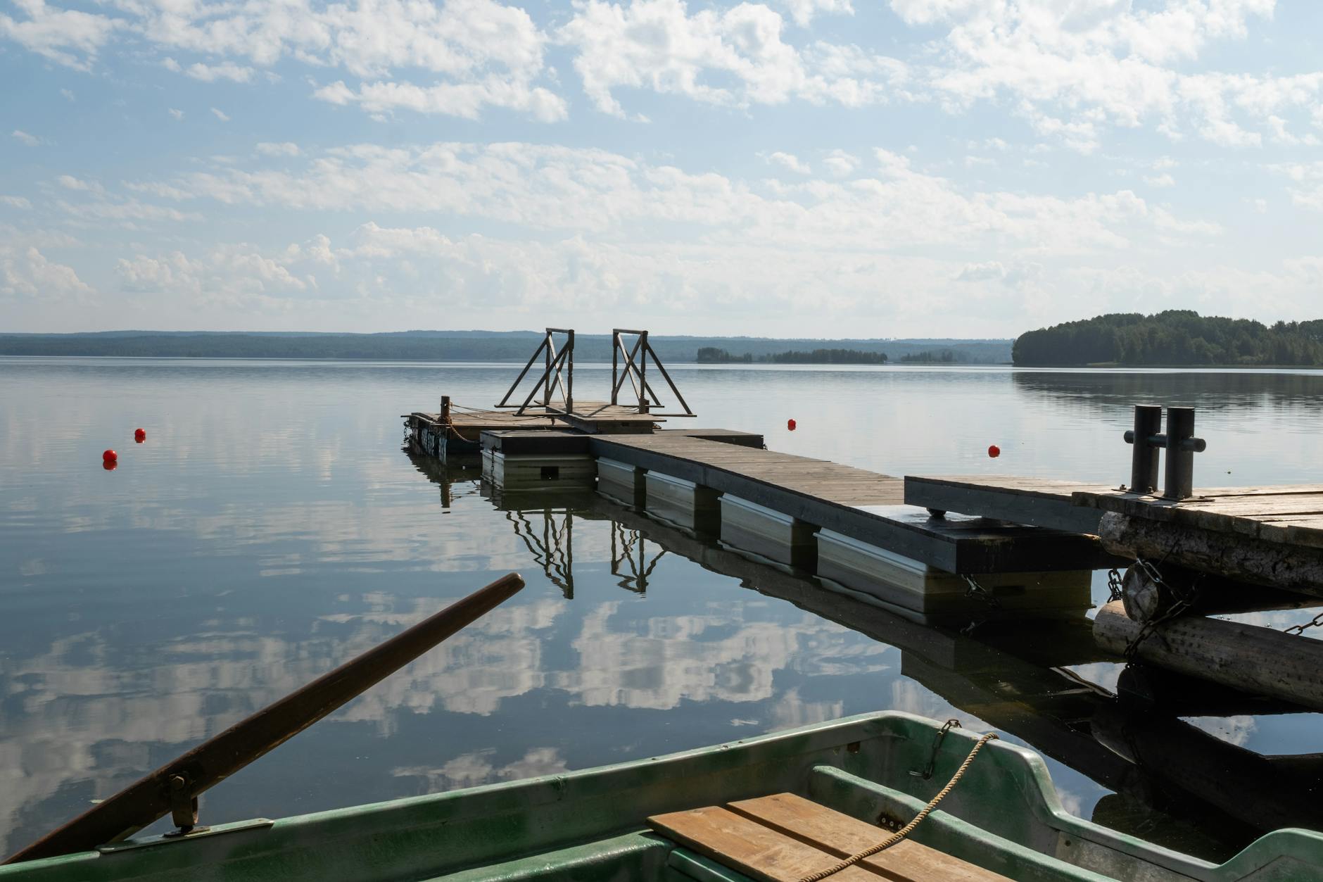 Drewniany pomost nad spokojnym jeziorem w słoneczny letni dzień