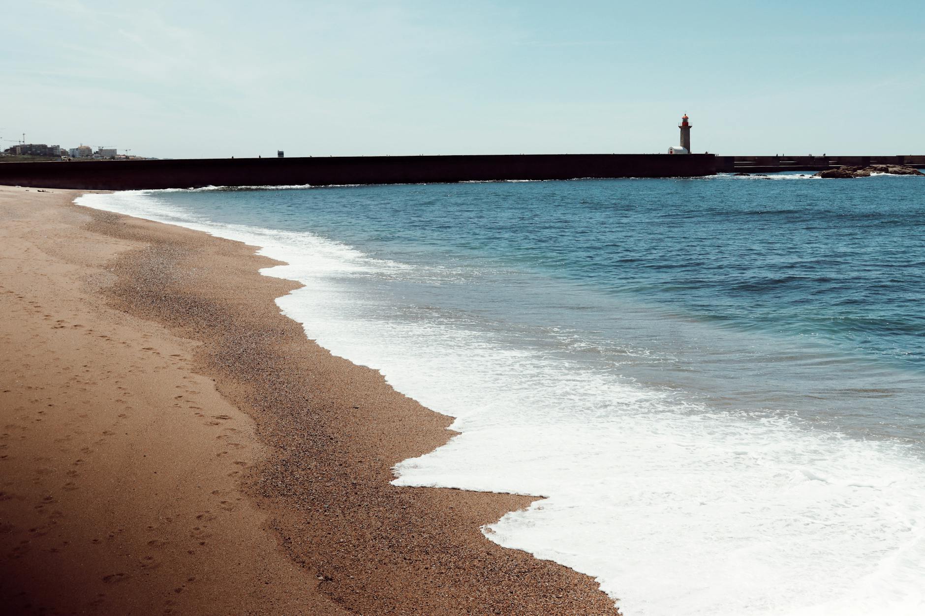 Latarnia morska nad spokojną plażą atlantycką o zachodzie słońca