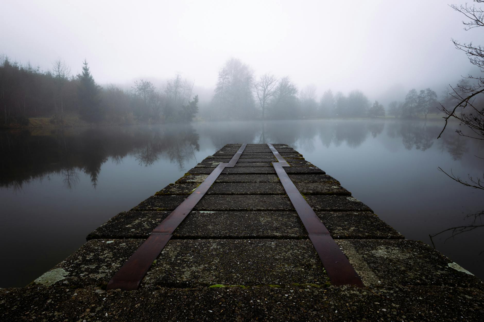Mglisty poranek nad austriackim jeziorem z drewnianym pomostem