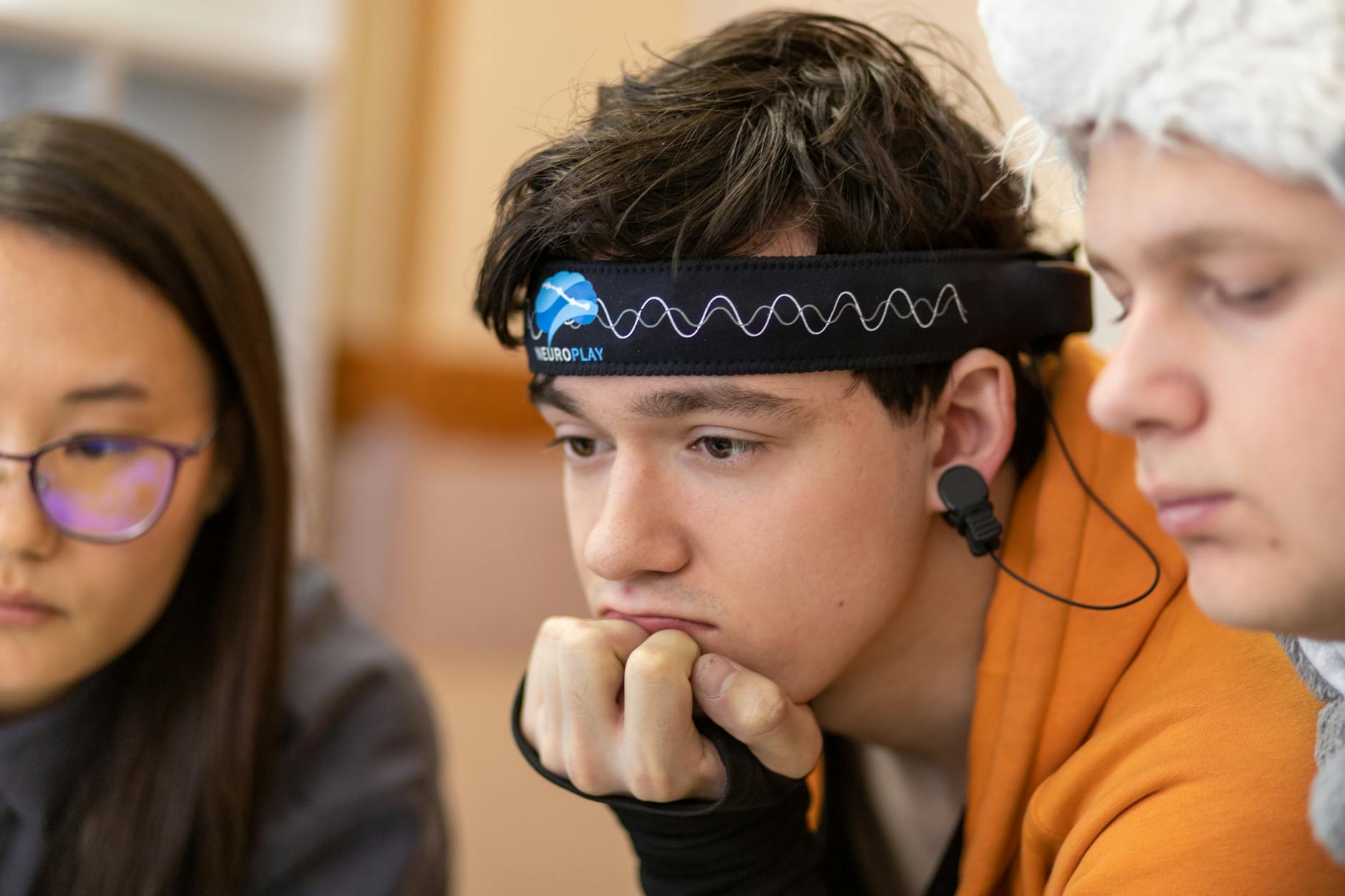 Nastolatkowie uczą się razem, jeden ma na głowie opaskę neurotech
