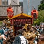 Japońskie matsuri bez tajemnic: jak przeżyć lokalne święto jak mieszkaniec Tłum w Tokio niesie tradycyjne mikoshi podczas kolorowego matsuri